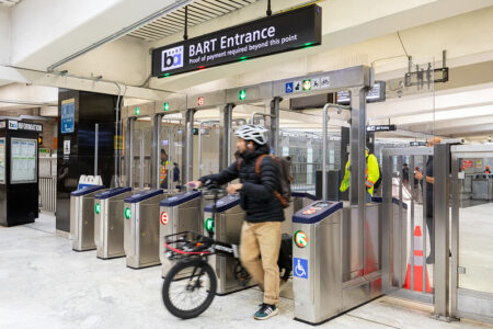 A cyclist walks through an upgraded fare gate on the BART system in this undated photo provided by the transit agency.