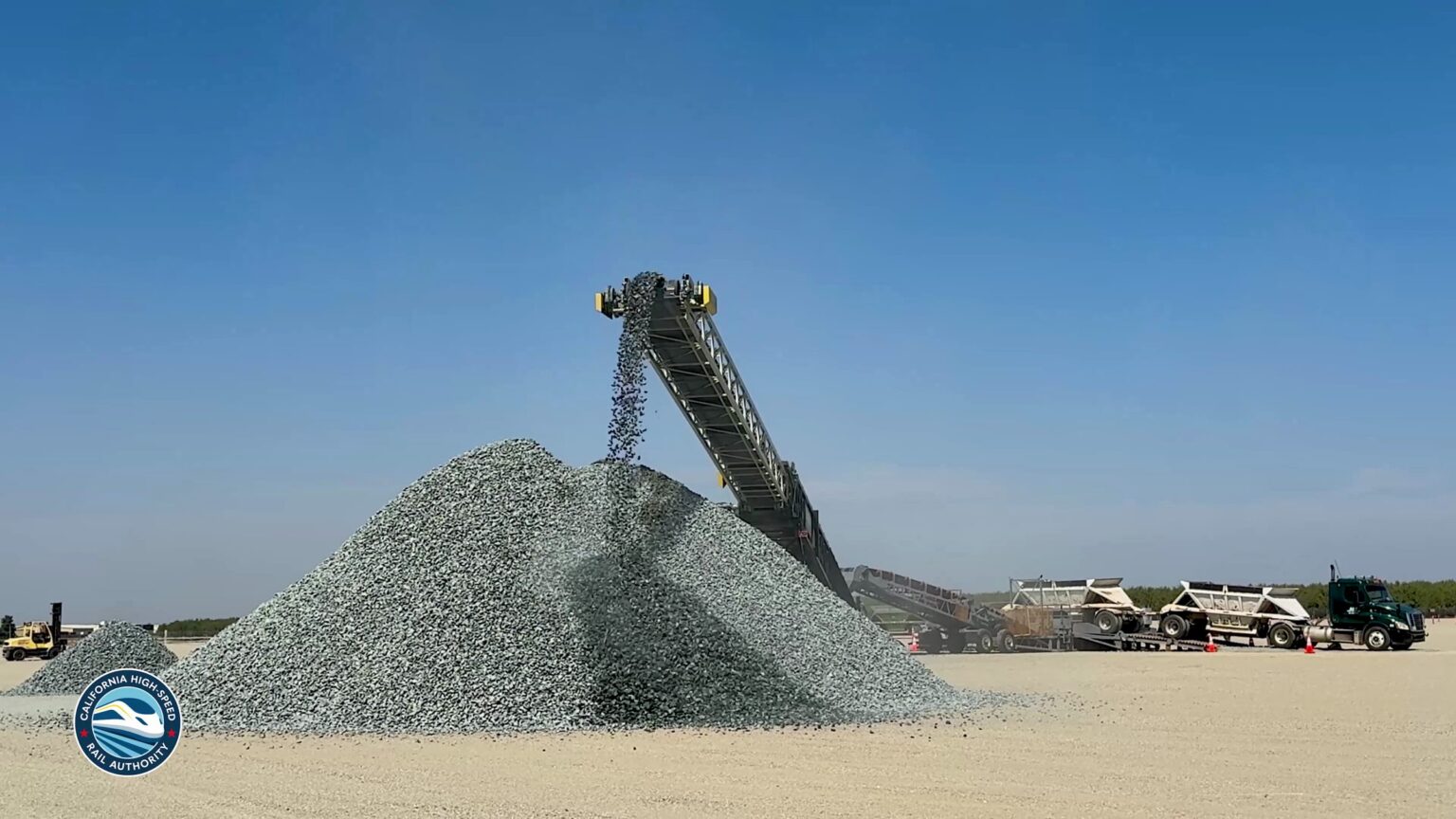 California High-Speed Rail loading up on materials ahead of first track installation Large pile of ballast rock beside a conveyor and trucks at a California High-Speed Rail construction site